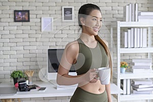 Young fitness woman in sportswear having a cup of coffee after exercising at home, Healthy and Lifestyles