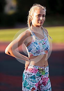 Young fitness woman is standing at stadium