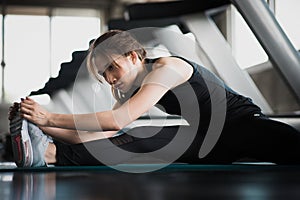 Young fitness woman stretching her leg to warm up at gym