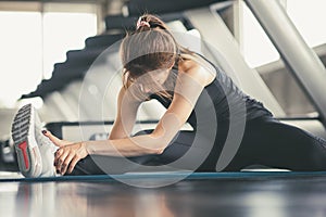 Young fitness woman stretching her leg to warm up at gym