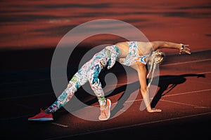 Young fitness woman is stretching at stadium