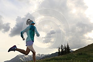 young fitness woman trail runner running on beautiful mountain peak