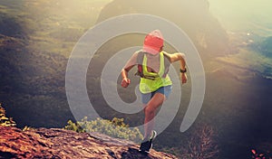 Fitness woman trail runner running up to mountain top