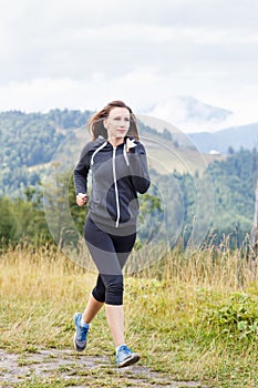 Young fitness woman trail running in mountains