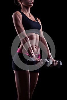 Young fitness woman in training pumping up muscles with dumbbell