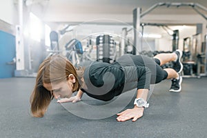 Young fitness woman working out doing push-ups on floor in sport gym. Sport, fitness, training, lifestyle and people concept