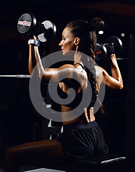 Young fitness woman working out with dumbbells weight in Gym. Diet and weight loss concept