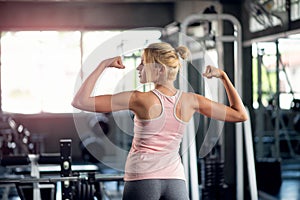 Young fitness woman workout in the gym, female model in sportswear showing her muscles
