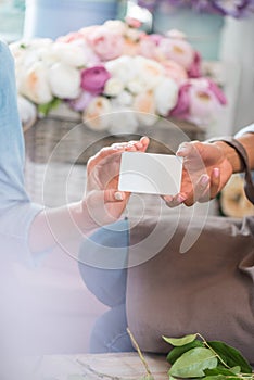 Young florists holding blank white card in flower shop