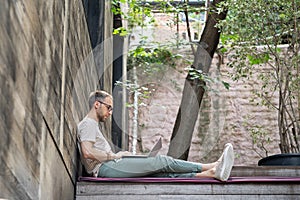 Young focused pensive European millennial guy freelancer working on laptop at outdoor workspace