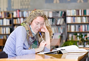 Young focused student using a tablet computer in a library