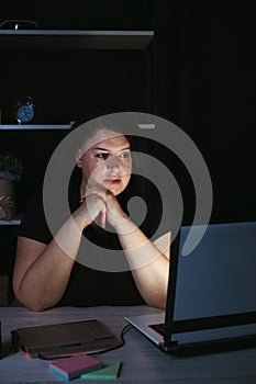 Young focused woman doing overtime job at night