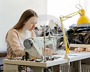 Focused female seamstress sewing clothes at her workplace