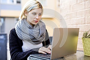 Young Focused Woman Working On Laptop At Outdoor Cafe