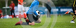 Young Football Goalkeeper Catching Soccer Ball. Soccer Goalie