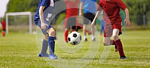 Young Football Players Kicking Ball on Soccer Field. Soccer Horizontal Background. Youth Junior Athletes in Red and Blue Soccer