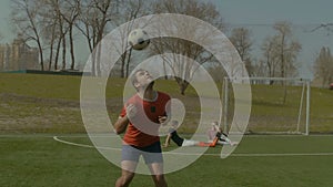 Young footballer heading soccer ball on the field