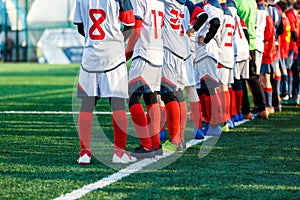 Young footballers boys dribble, kick football ball in game. Boys in red white sportswear running on soccer field.Training