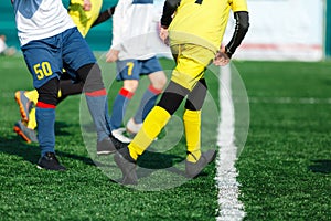 Young footballers dribble and kick football ball in game. Boys in yellow white sportswear running on soccer field.Training