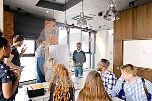 Young foreign guy is giving presentation for multi-ethnic audience