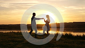 Young free couple dancing at sunset on beach. Happy guy and girl waltz in evening in a summer park. Enamored man and