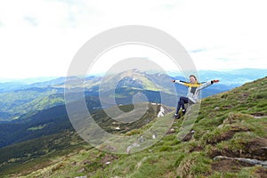 Young free female tourist wearing yellow jacket sitting in Appenine mountains.