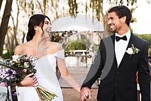 Young, free and in love. Shot of a happy newlywed young couple holding hands together outdoors on their wedding day.