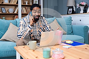 Young freelance business man or exchange student working remotely from his home office on laptop computer. African American work