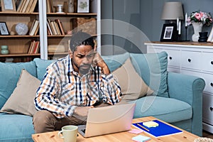 Young freelance business man or exchange student working remotely from his home office on laptop computer. African American work