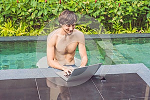 Young freelancer working on vacation next to the swimming pool