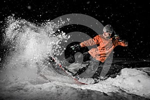 Young freeride snowboarder jumping in snow at night