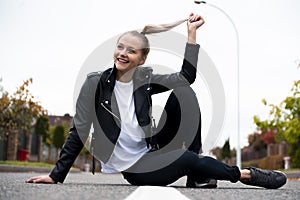 Young fresh cheerful hipster young woman sitting on the road in countryside wearing stylish summer clothes. Bright bag pack. Warm