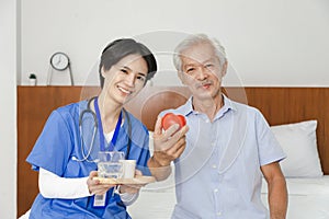 Young friendly asian female caregiver look at camera to happy senior man in nursing home