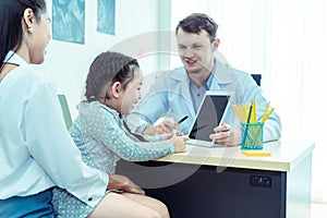 Young friendly caucasian pediatrician doctor is examining child patient girl with her mother ,consultation with a stethoscope and
