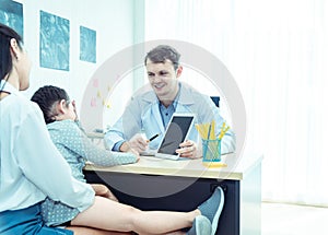 Young friendly caucasian pediatrician doctor is examining child patient girl with her mother ,consultation with a stethoscope and