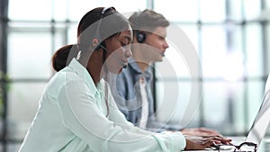 Young friendly operator woman agent with headsets working in a call center