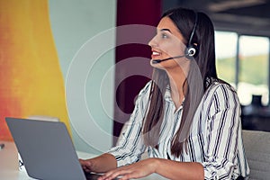 Young friendly operator woman agent with headsets working in a call centre.