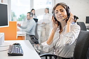 Young friendly operator woman agent with headsets working in a call centre.