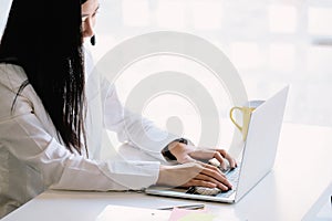 Young friendly operator woman agent with headsets working with laptop computer in a call center