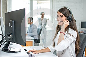 Young friendly operator woman agent with headsets working in a call centre