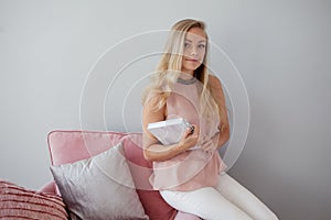 Young friendly woman sitting in a chair with a notebook in her hands. A nice companion.