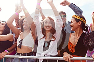 Young Friends In Audience Behind Barrier Dancing And Singing At Outdoor Festival Enjoying Music