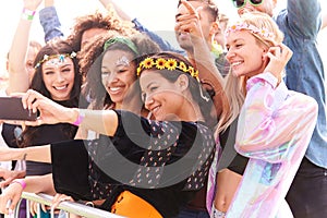 Young Friends In Audience Behind Barrier At Outdoor Music Festival Posing For Selfie
