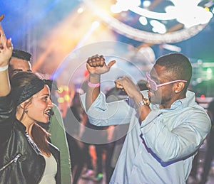 Young friends dancing at party in night club - Diverse culture people enjoying weekend nightlife with original laser lights colors