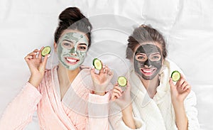 Young friends with facial  having fun on bed at pamper party, top view