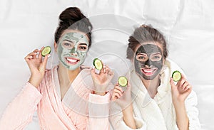 Young friends with facial  having fun on bed at pamper party, top view photo
