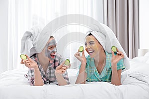 Young friends with facial masks having fun in bedroom