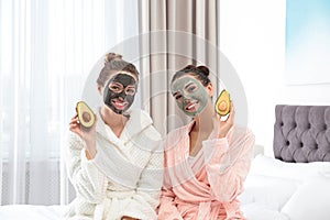 Young friends with facial masks having fun in bedroom