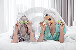 Young friends with facial masks having fun in bedroom