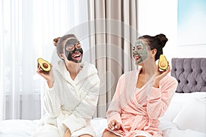 Young friends with facial masks having fun in bedroom